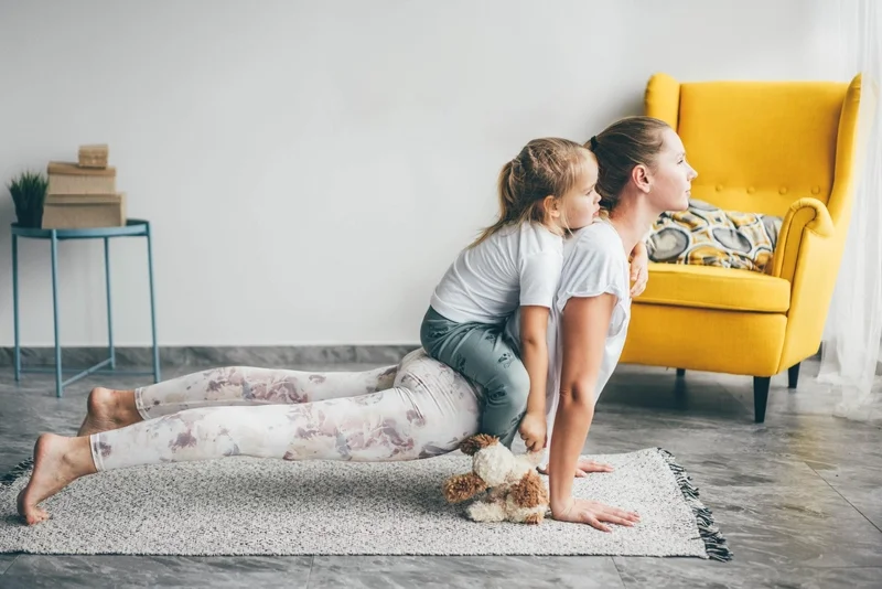 East Coast Telepsychiatry - 10 Great Ways to Improve Your Mental Health. Mother with daughter practicing yoga exercises at home.